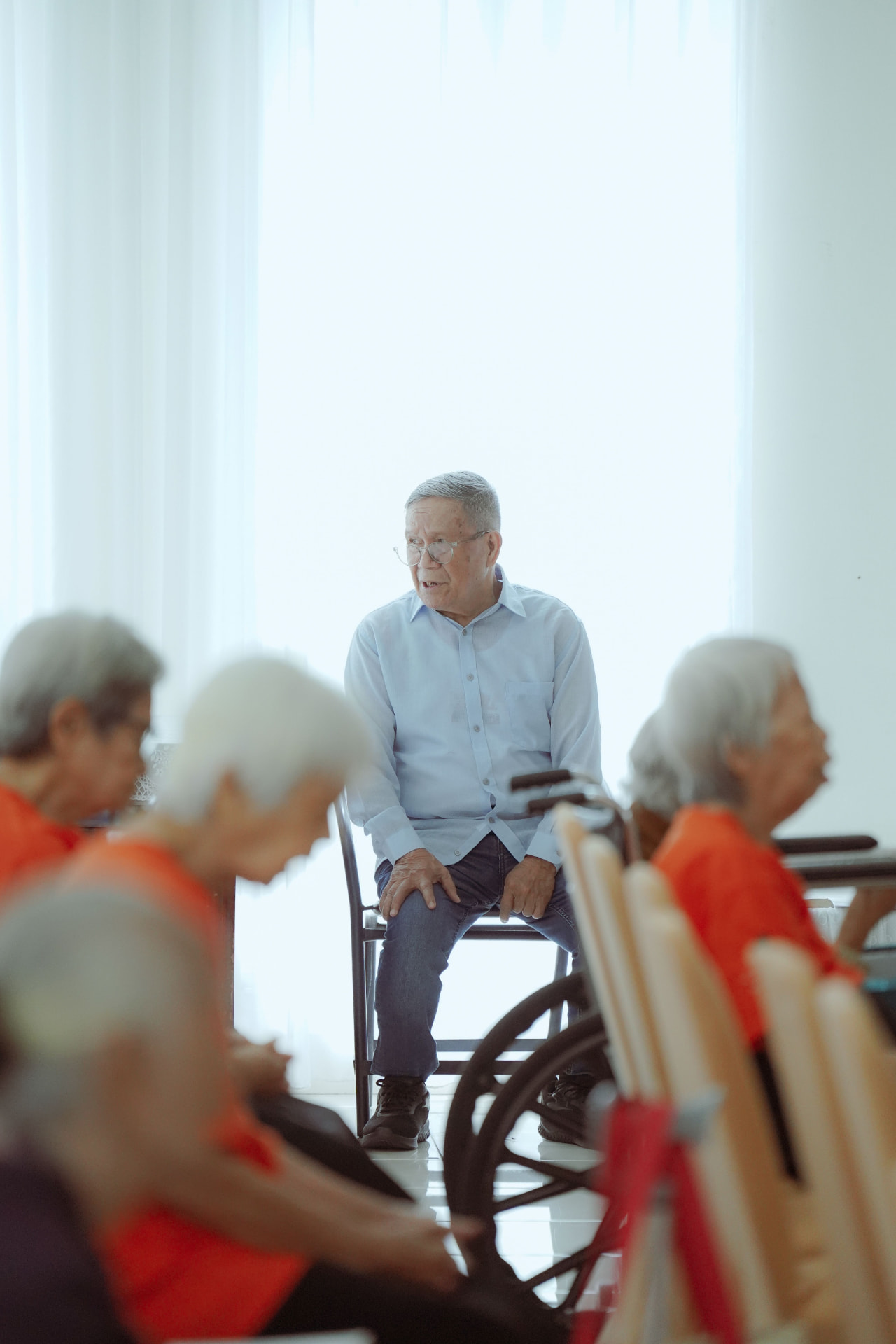Älterer Mann sitzt in einem hellen Gemeinschaftsraum im Gespräch