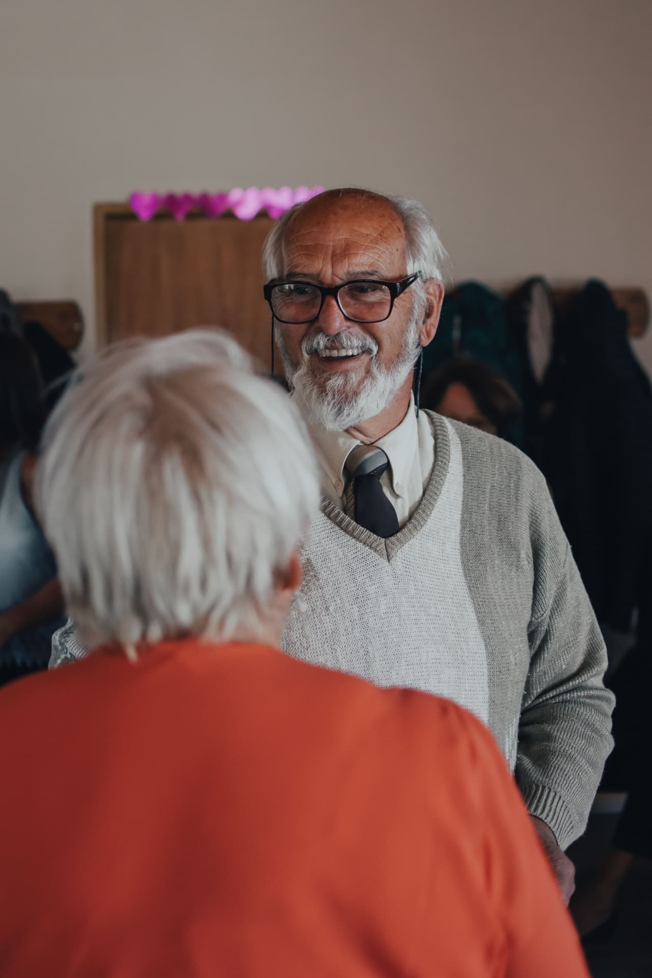 Älterer Mann mit Brille lächelt seiner Gesprächspartnerin zu