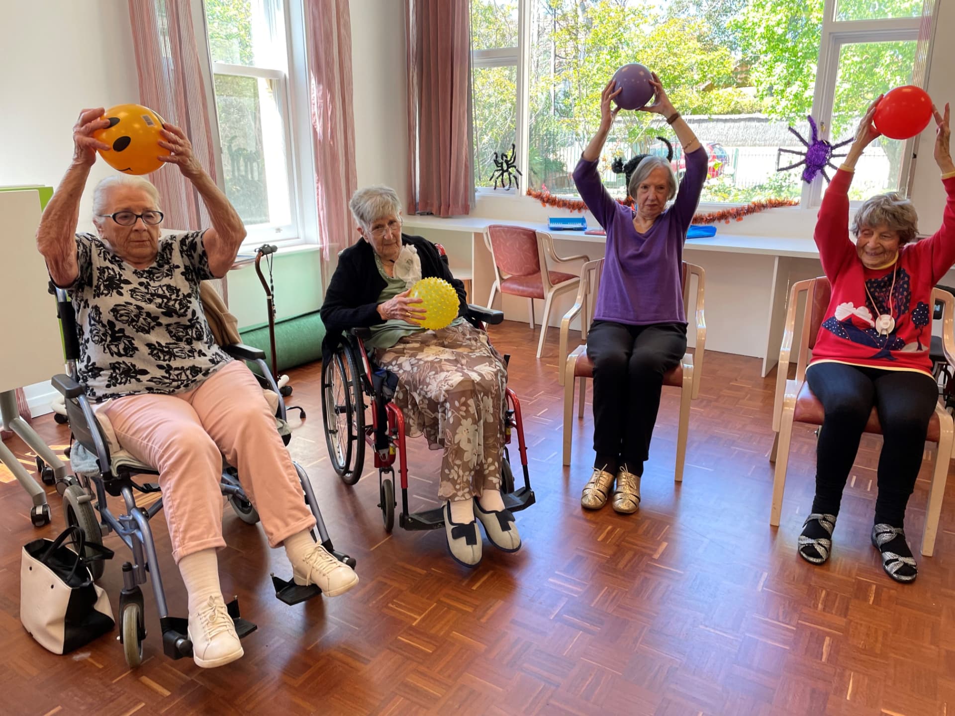 Ältere Frauen halten bei einer Gruppenaktivierung bunte Bälle in die Höhe