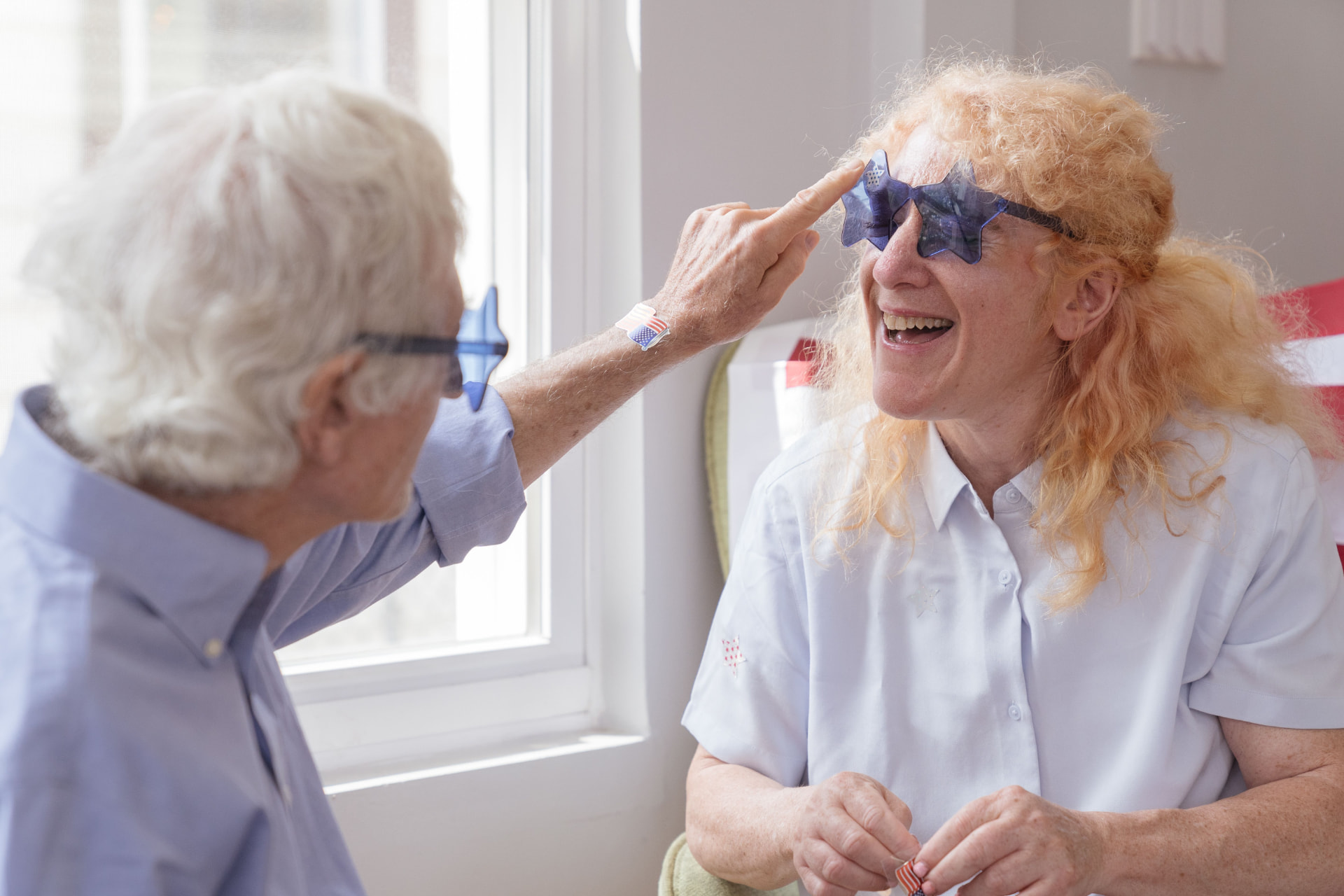 Zwei ältere Menschen lachen gemeinsam am Fenster