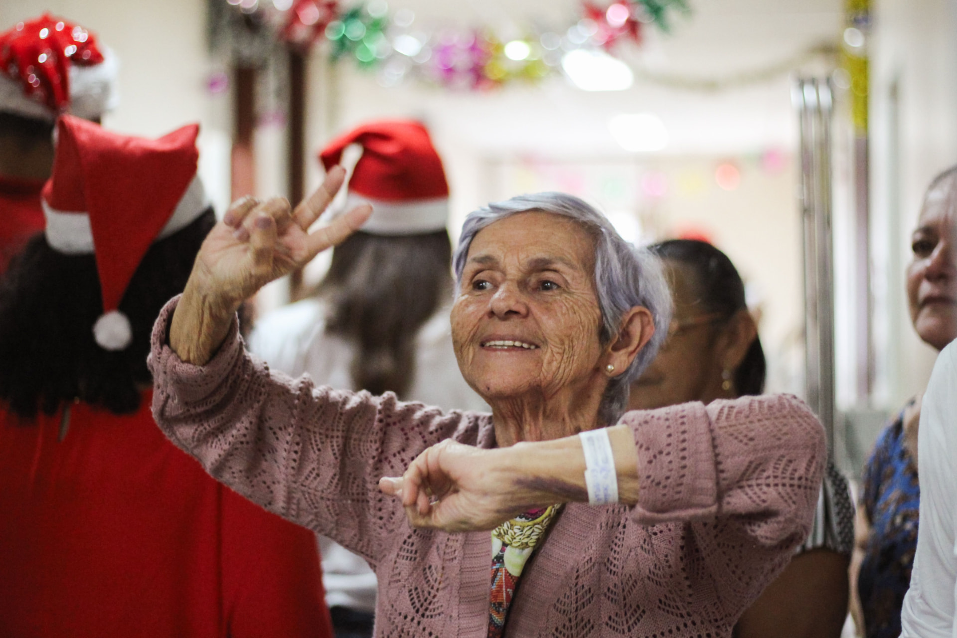 Ältere Frau tanzt bei einer Weihnachtsfeier mit anderen Gästen